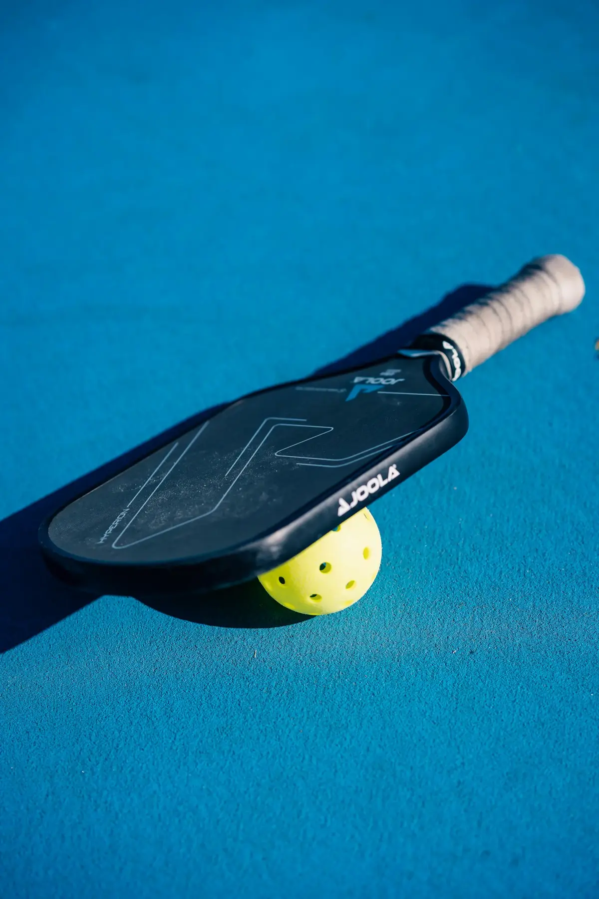 Raquette et balle de pickleball sur terrain bleu