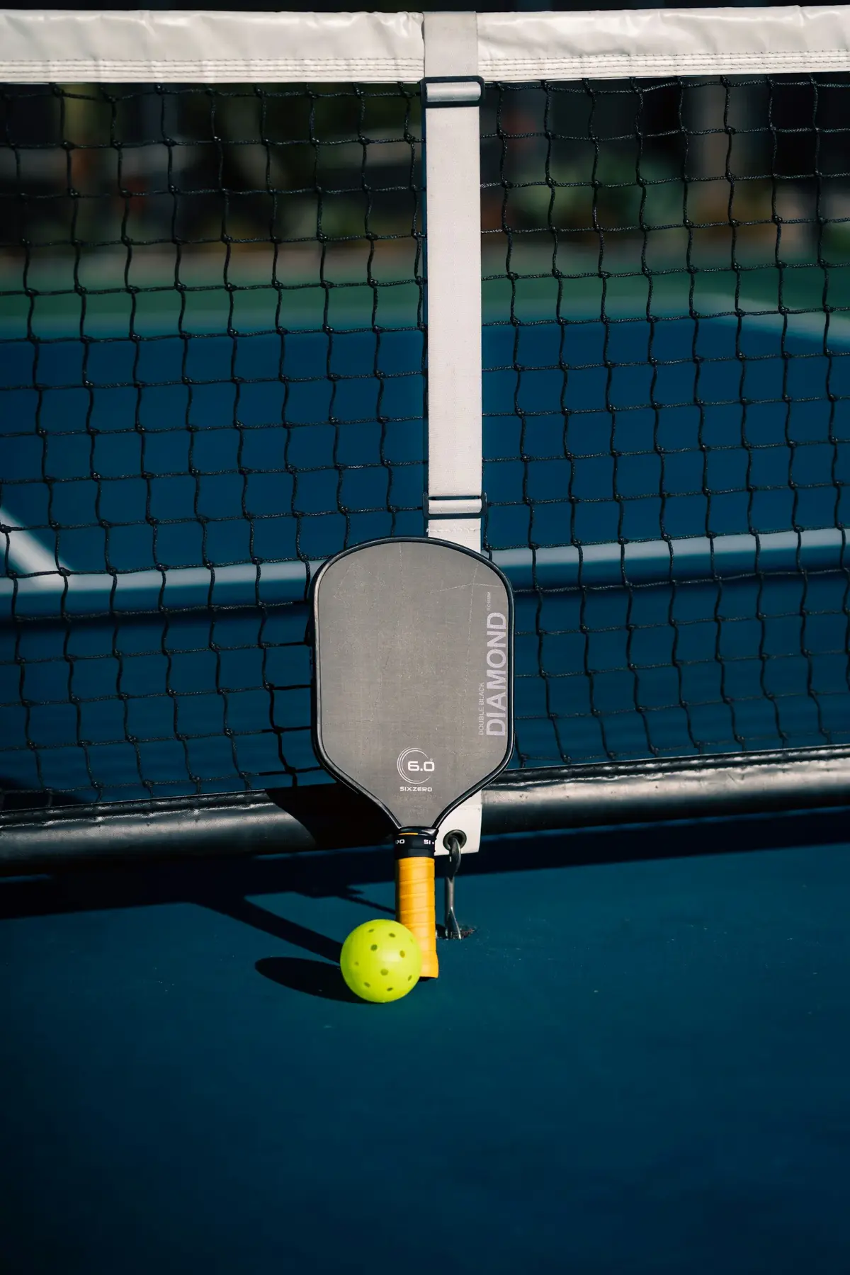 Raquette et balle de pickleball posées sur le filet